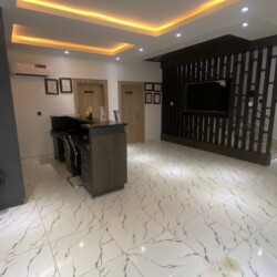 Skintisfaction Lobby Featuring Marbled Floors, Warm Ambient Lighting, Sleek Reception Desk, And Stylish Wooden Accent Wall. Skintisfaction Lobby With Marbled Floors, Wooden Accent Wall, Sleek Reception, And Warm Led Lighting.