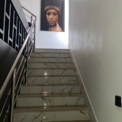 Modern Minimalist Staircase With Glossy Tiles And A Striking Traditional Portrait At The Top, Illuminated By Bright Natural Light. Contemporary Staircase With Artistic Portrait And Sleek Design, Bright Natural Light, Elegant Minimalist Decor.