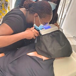 A Stylist Performs A Professional Hair Treatment In A Modern Salon With Attentive Colleagues In The Background. Professional Hairstyling And Hair Treatment Session At A Modern Salon.